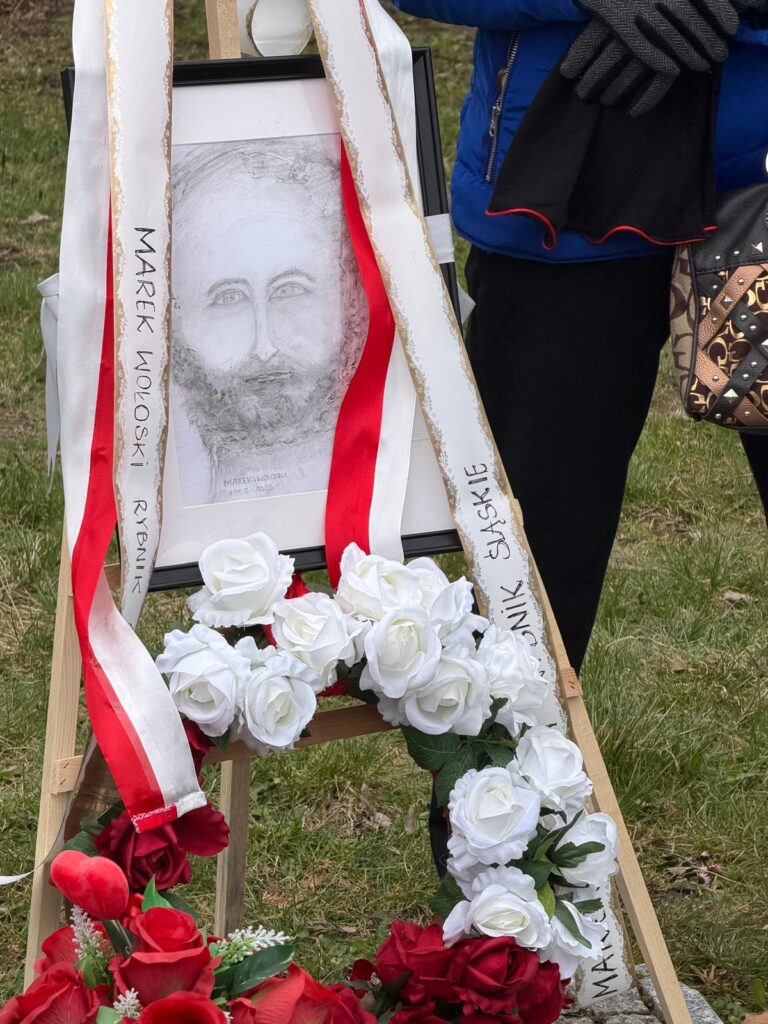 Uroczysta ceremonia pożegnania donatora ciała, Marka Wołoskiego z Rybnika. Portret na sztaludze ozdobiony białymi i czerwonymi różami oraz szarfami.